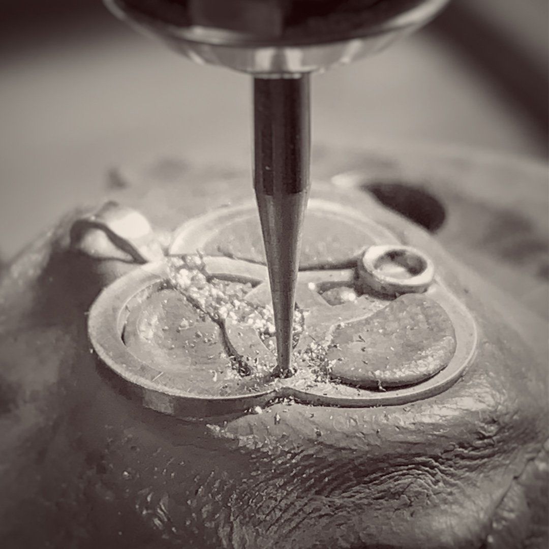 A black and white photo of a machine cutting a piece of clay.