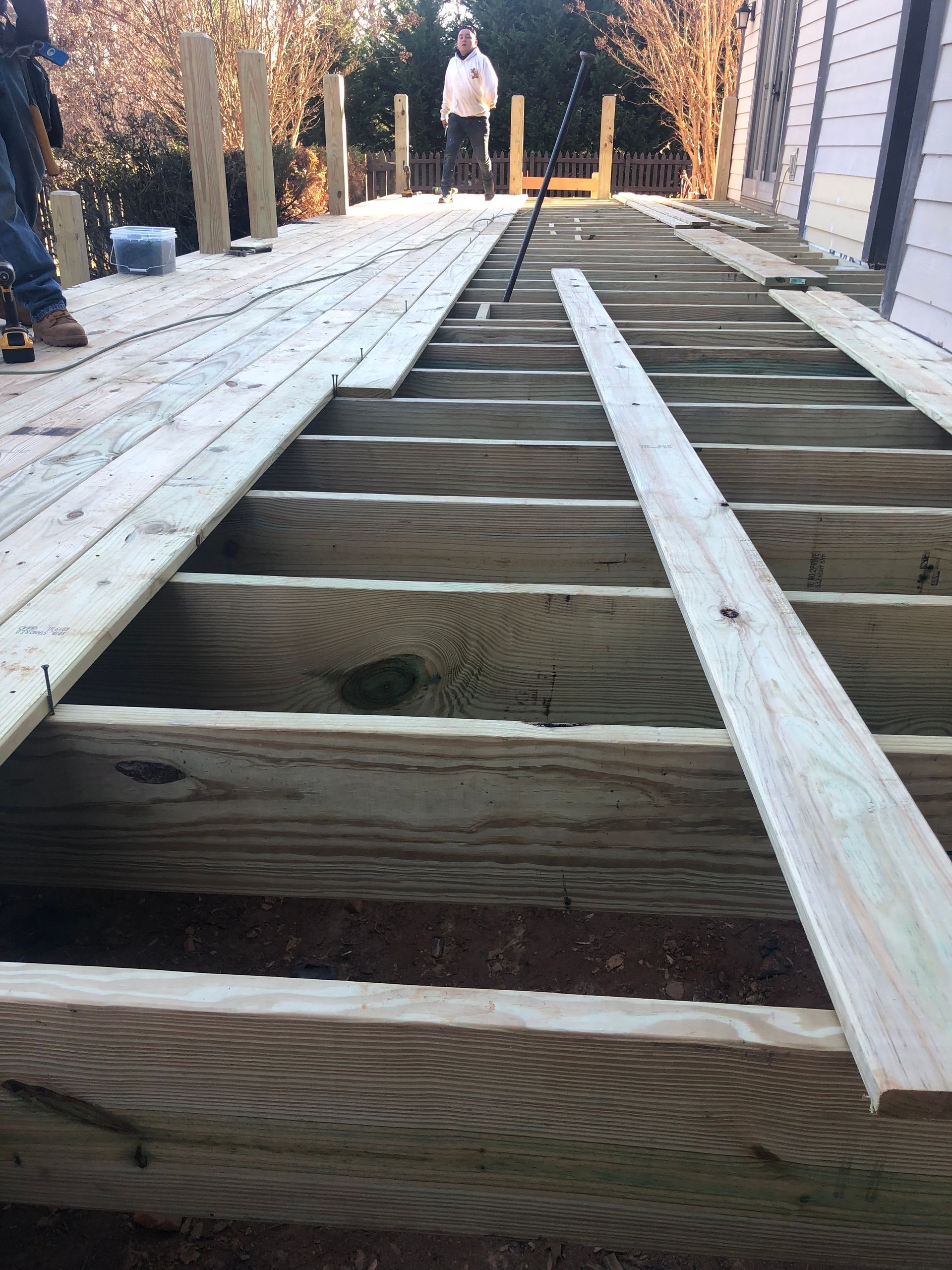 A person is standing on top of a wooden deck under construction.