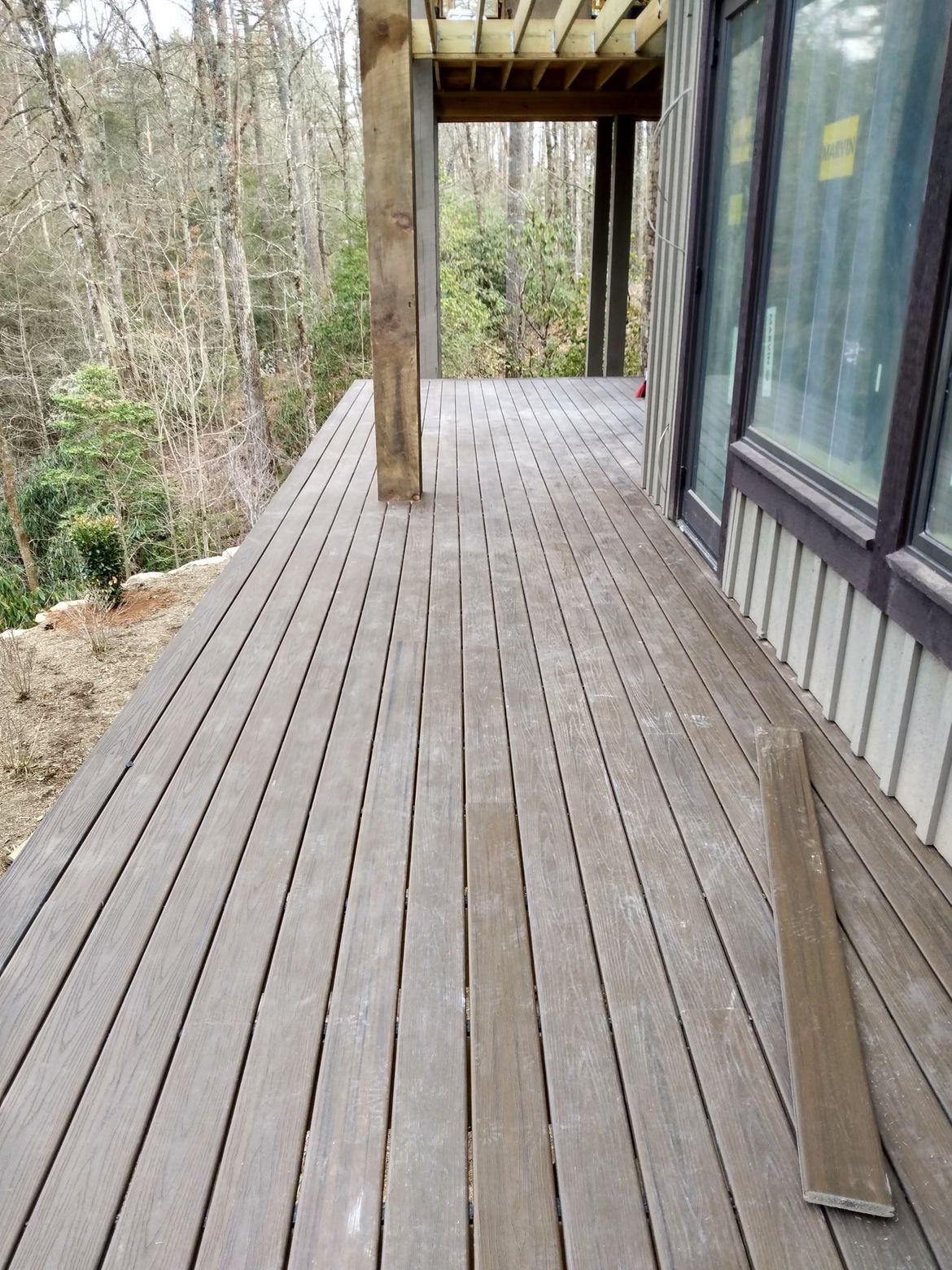 A wooden deck with a window and trees in the background.