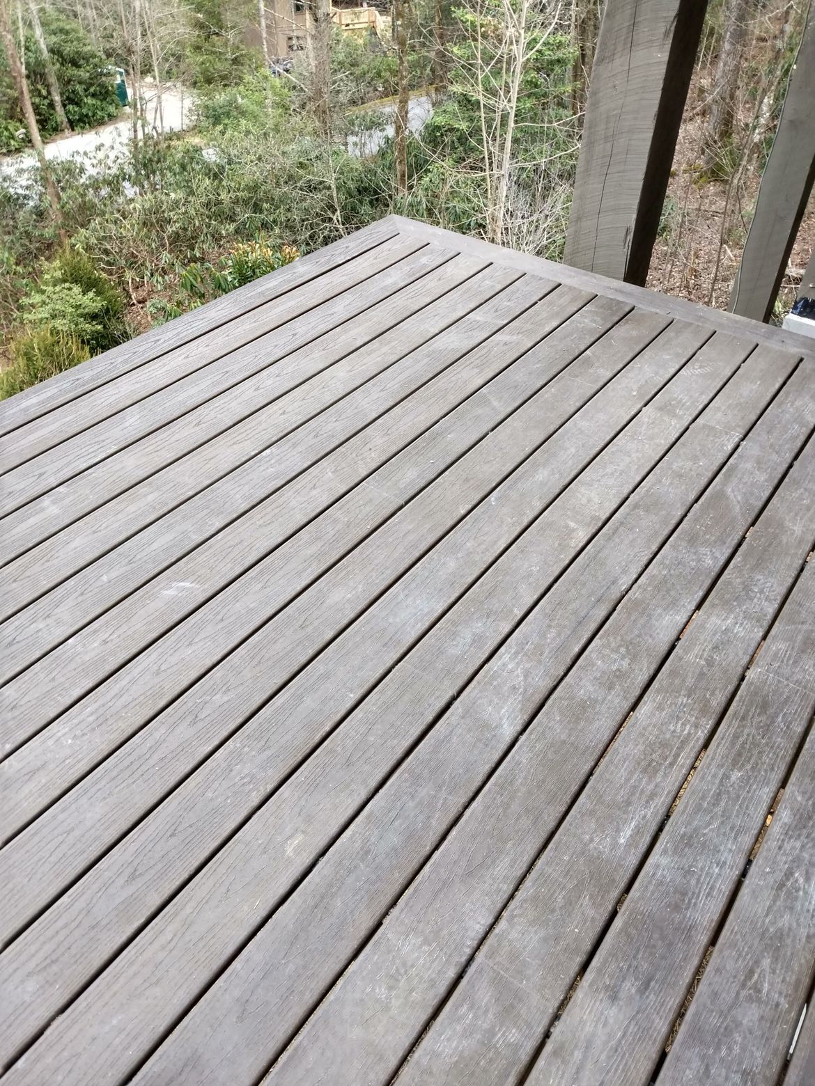 A close up of a wooden deck with trees in the background.