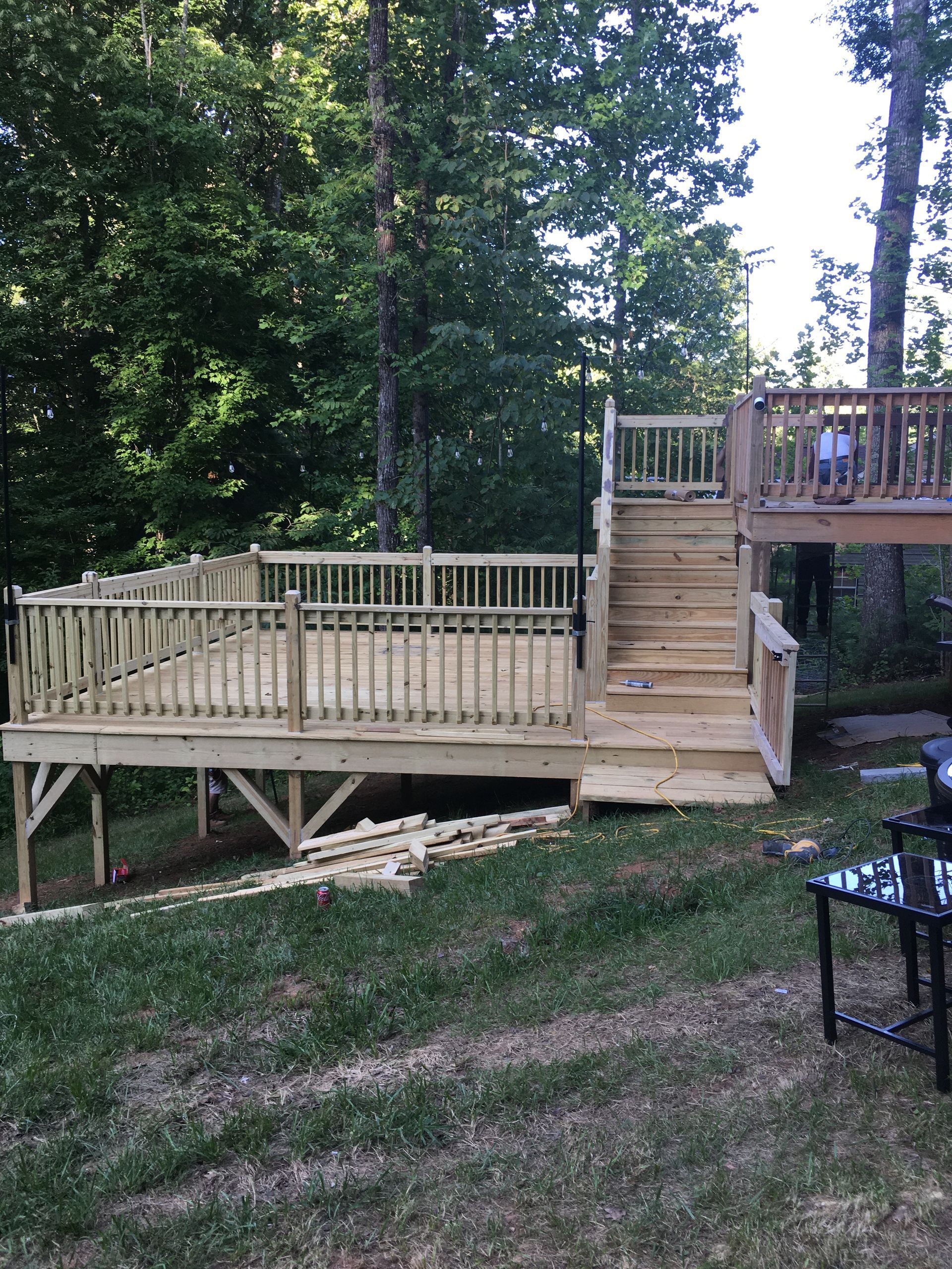 A wooden deck with stairs leading up to it is surrounded by trees.