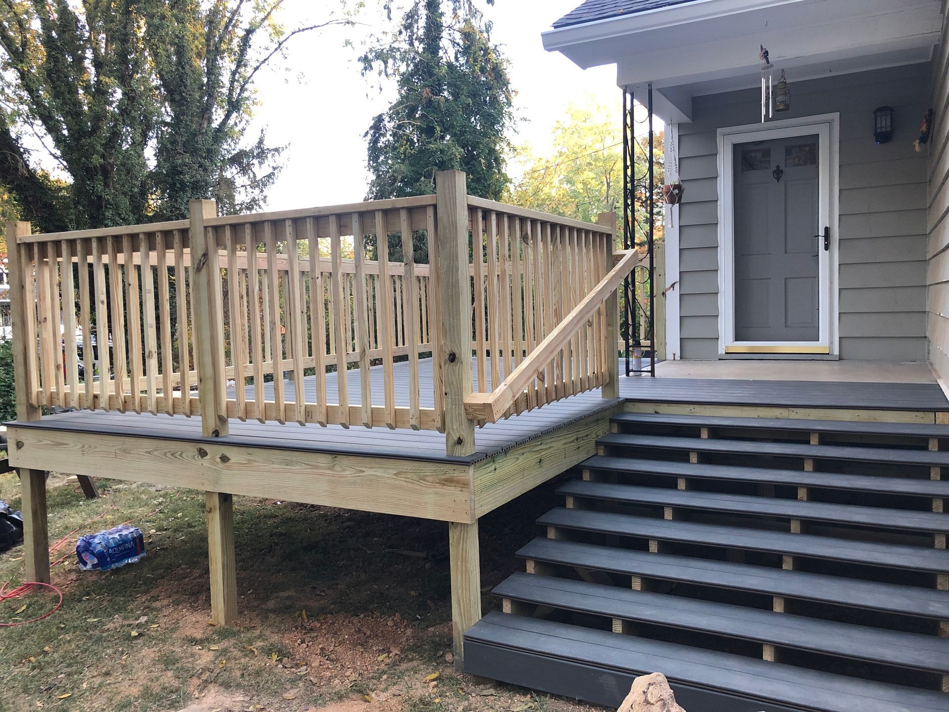 A wooden deck with stairs leading to the front door of a house.