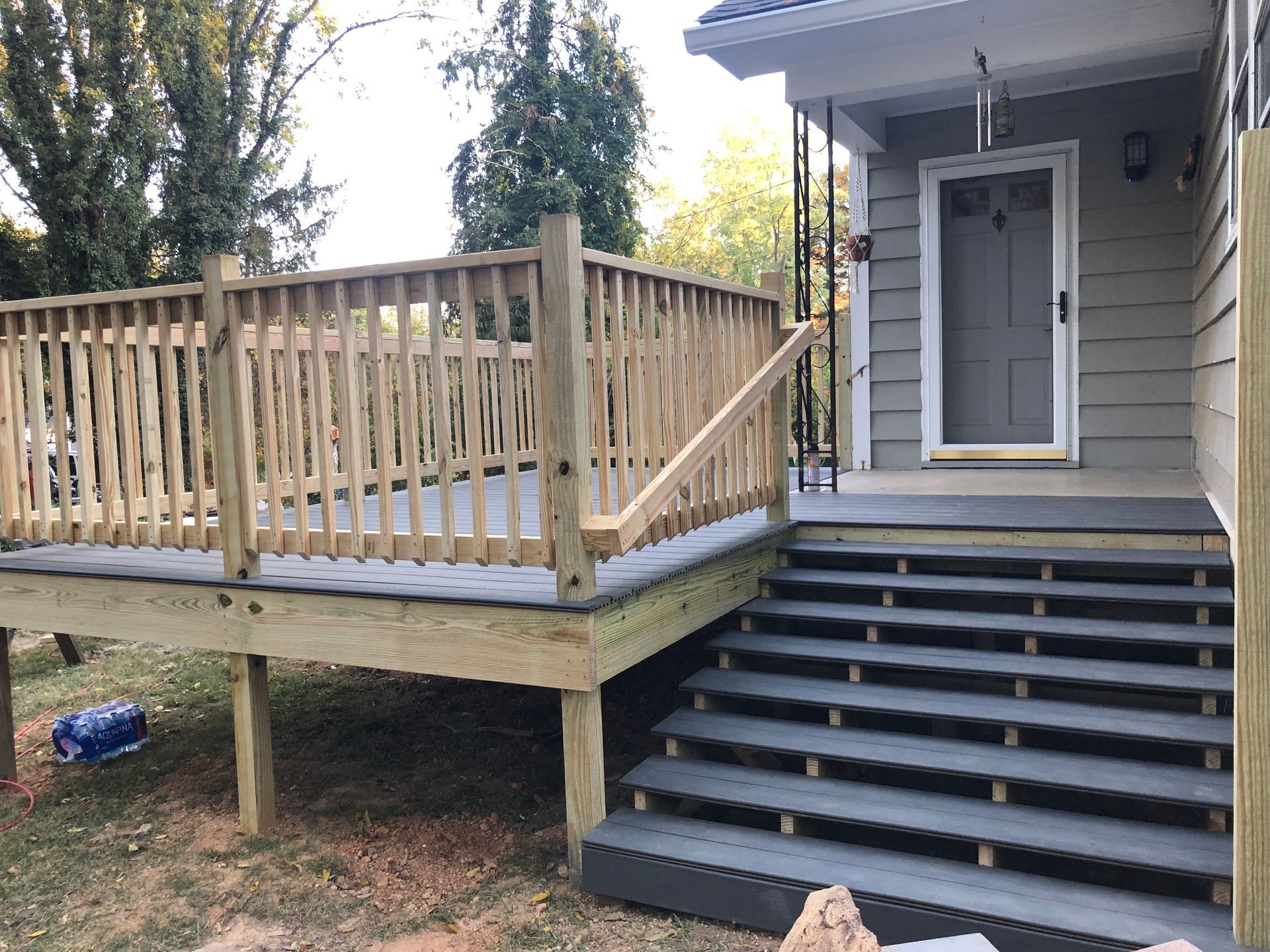 A wooden deck with stairs leading to the front door of a house.