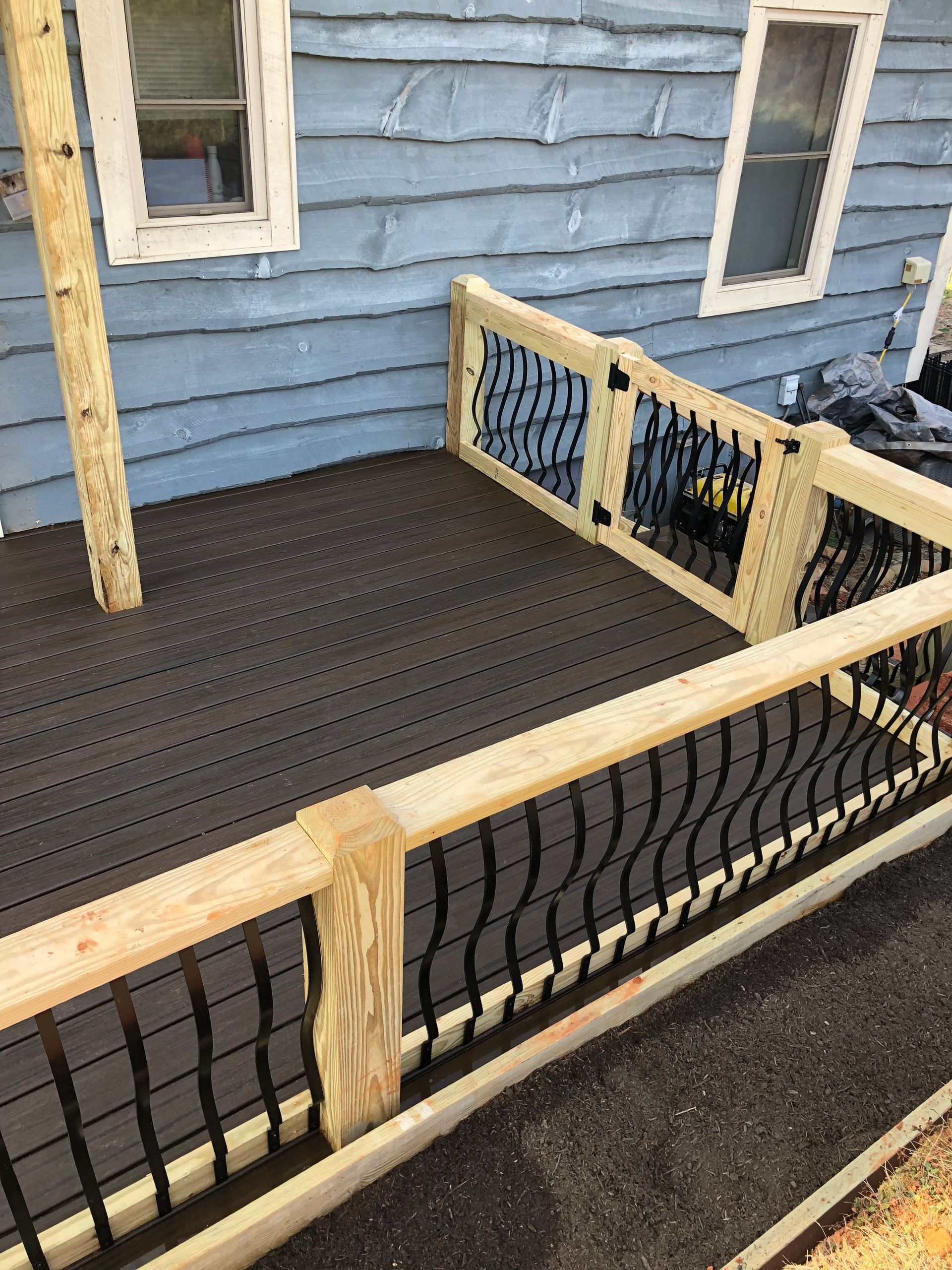 A wooden deck with a metal railing is being built on the side of a house.
