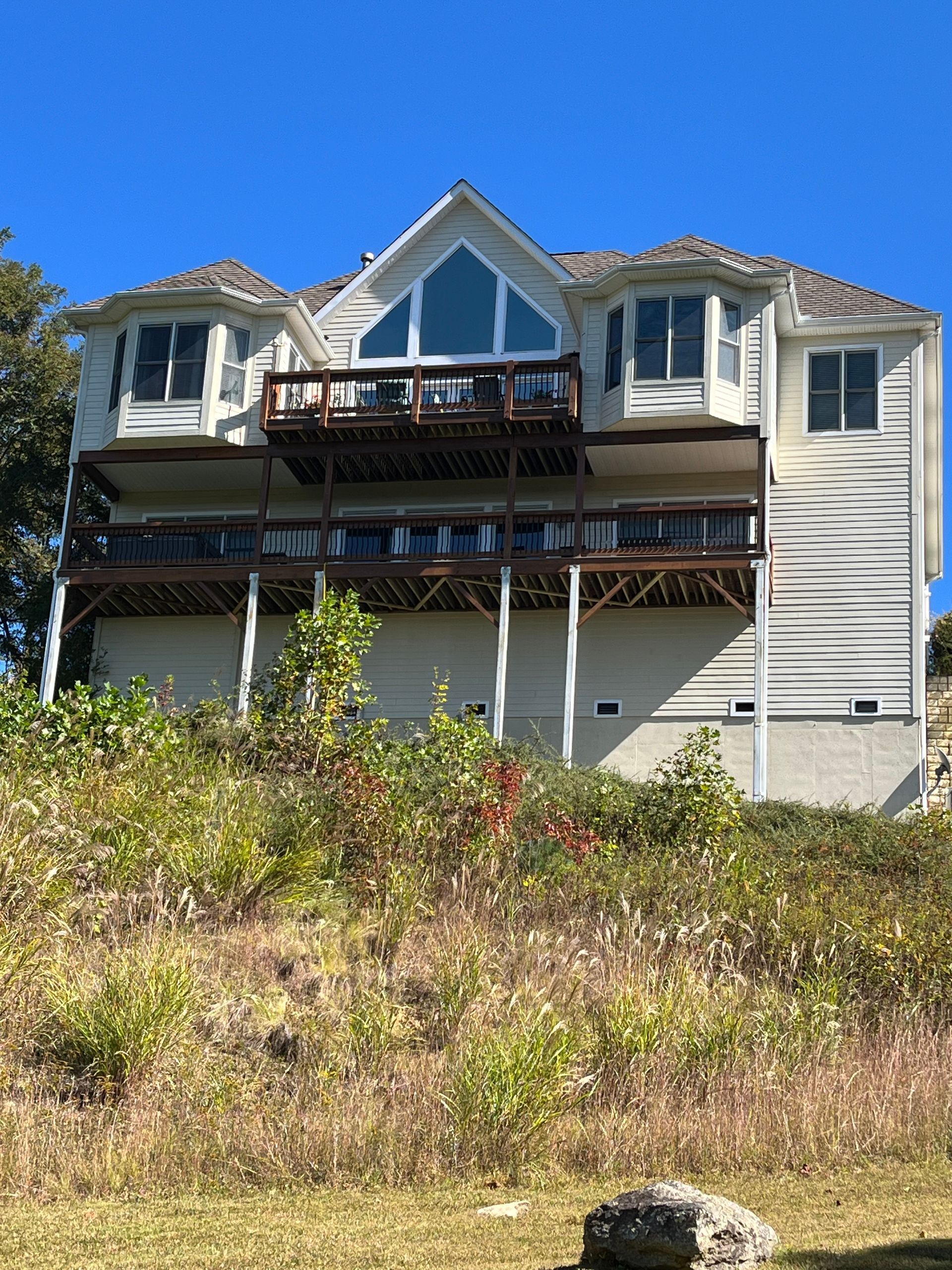 A large white house is sitting on top of a grassy hill.