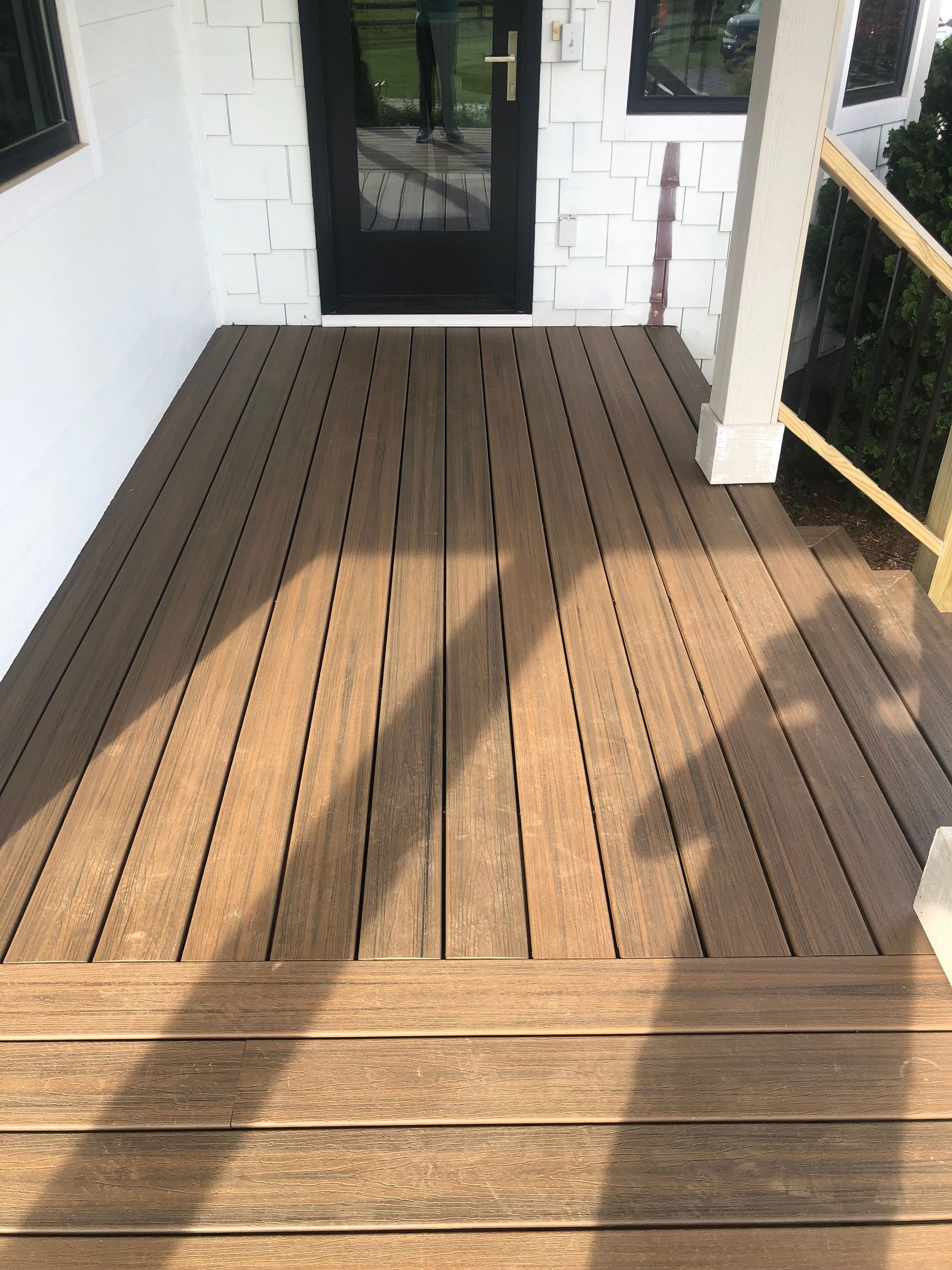 A wooden deck with a black door in the background