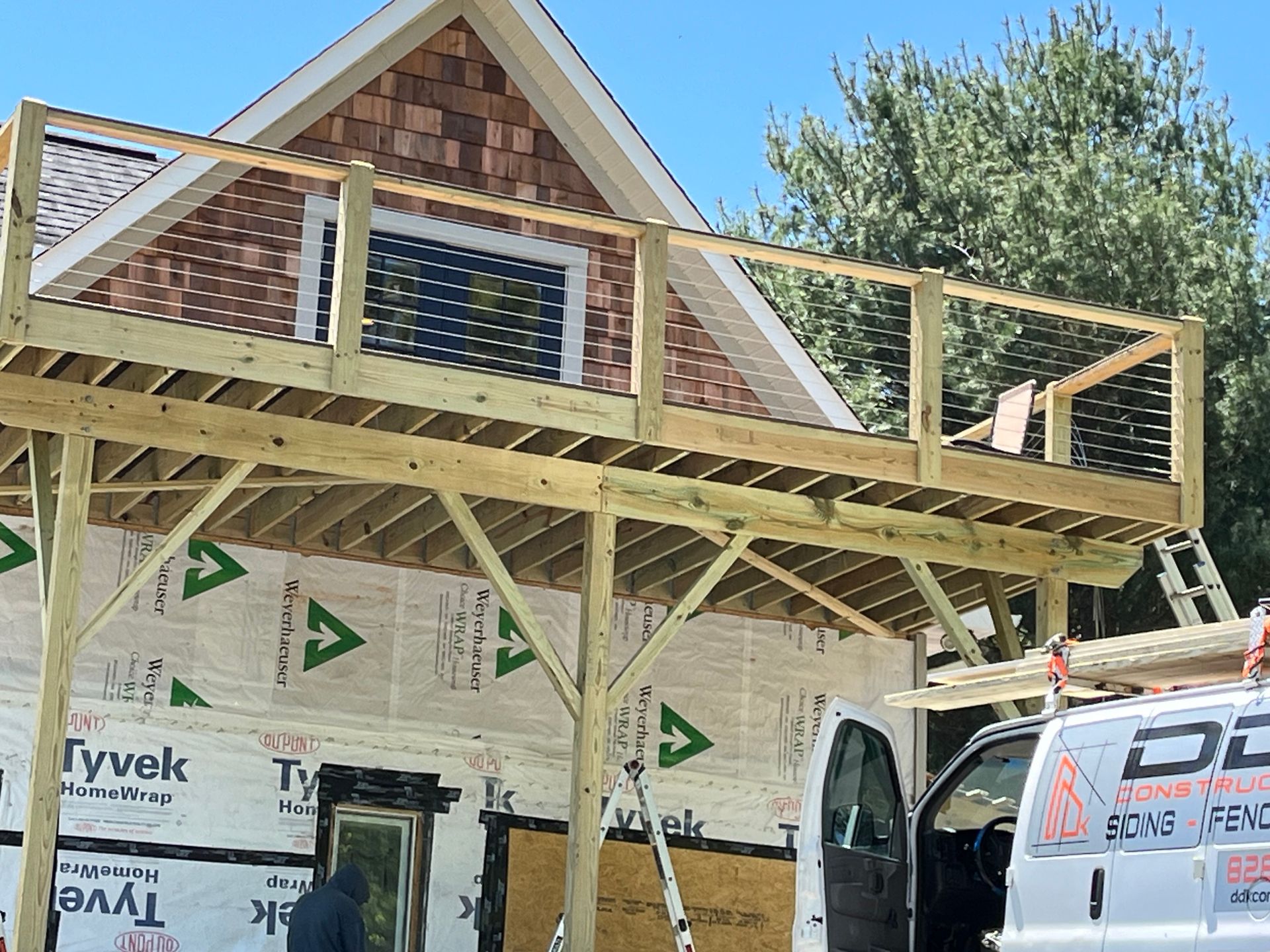 A white van is parked in front of a house under construction.