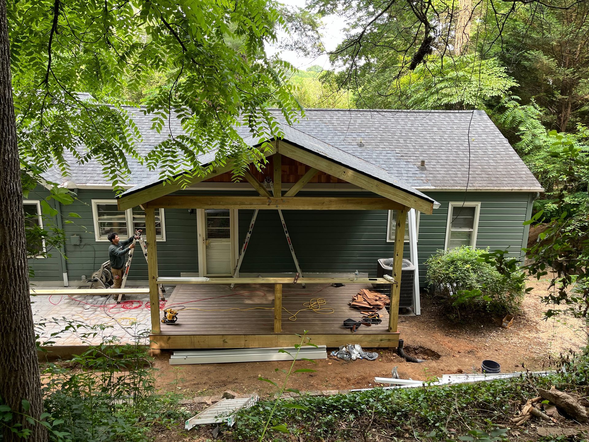 A man is working on a porch in front of a house.