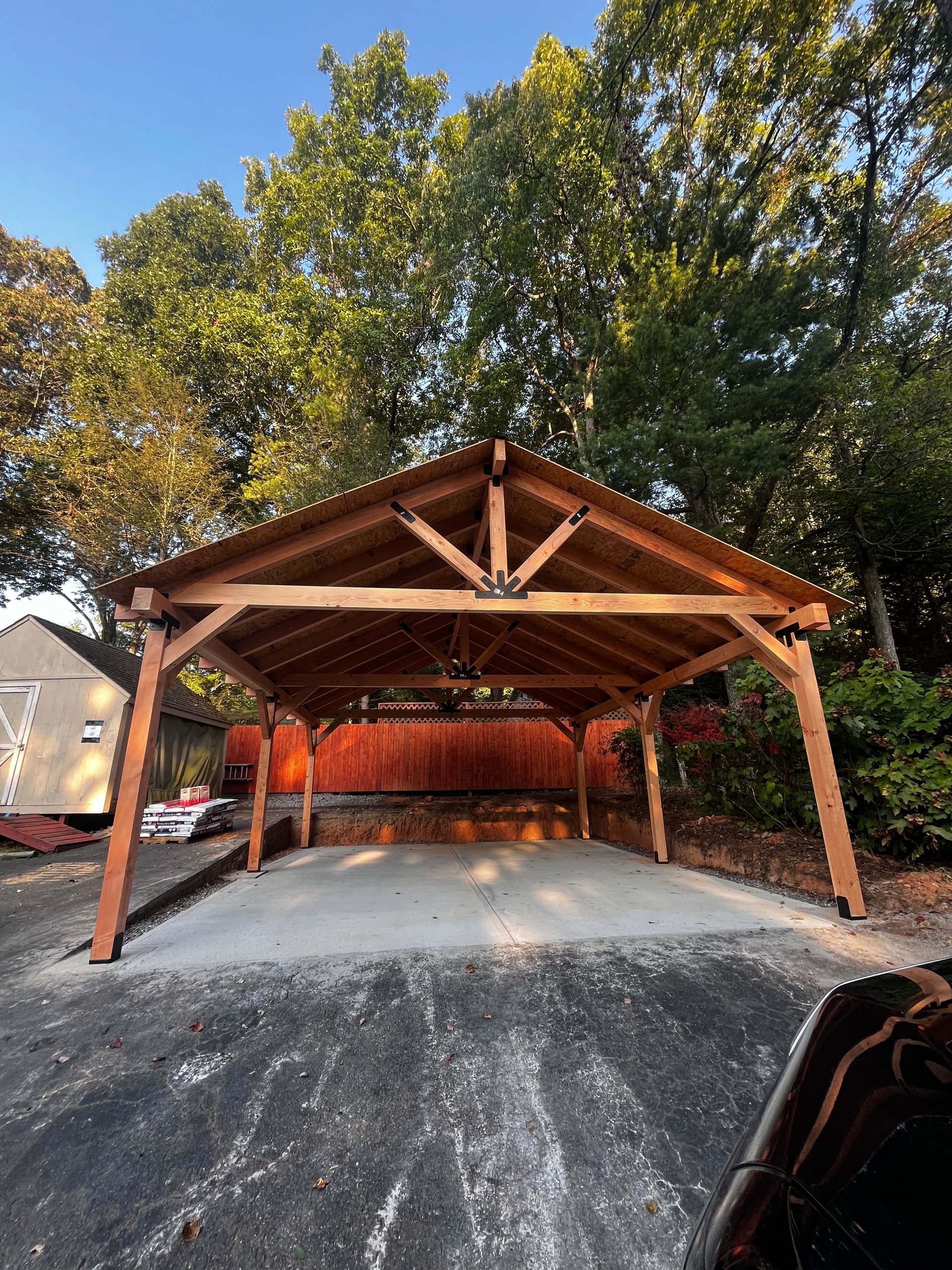A wooden carport is sitting on top of a concrete driveway.