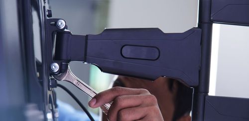 Person using a wrench to secure a TV bracket to a television.