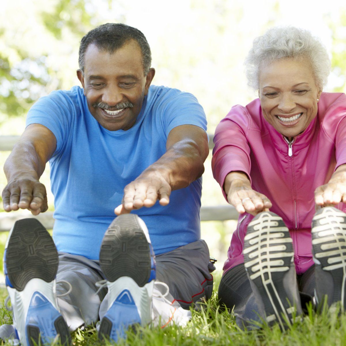A man and a woman are stretching their legs in the grass