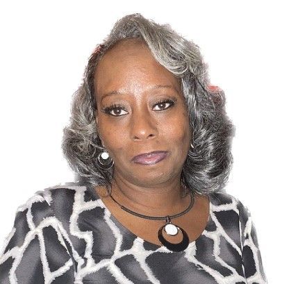 A woman with gray hair is wearing a necklace and earrings.