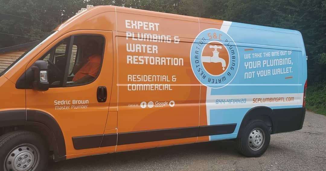 An orange and blue van is parked on a gravel road.