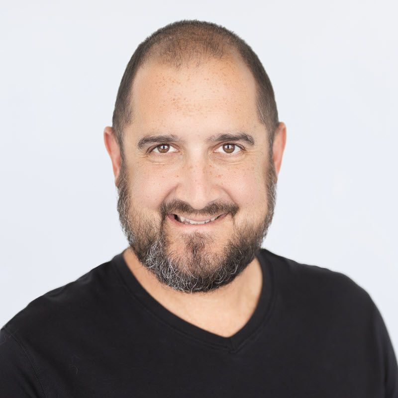 Agent Aaron with a beard is wearing a black shirt and smiling for the camera.