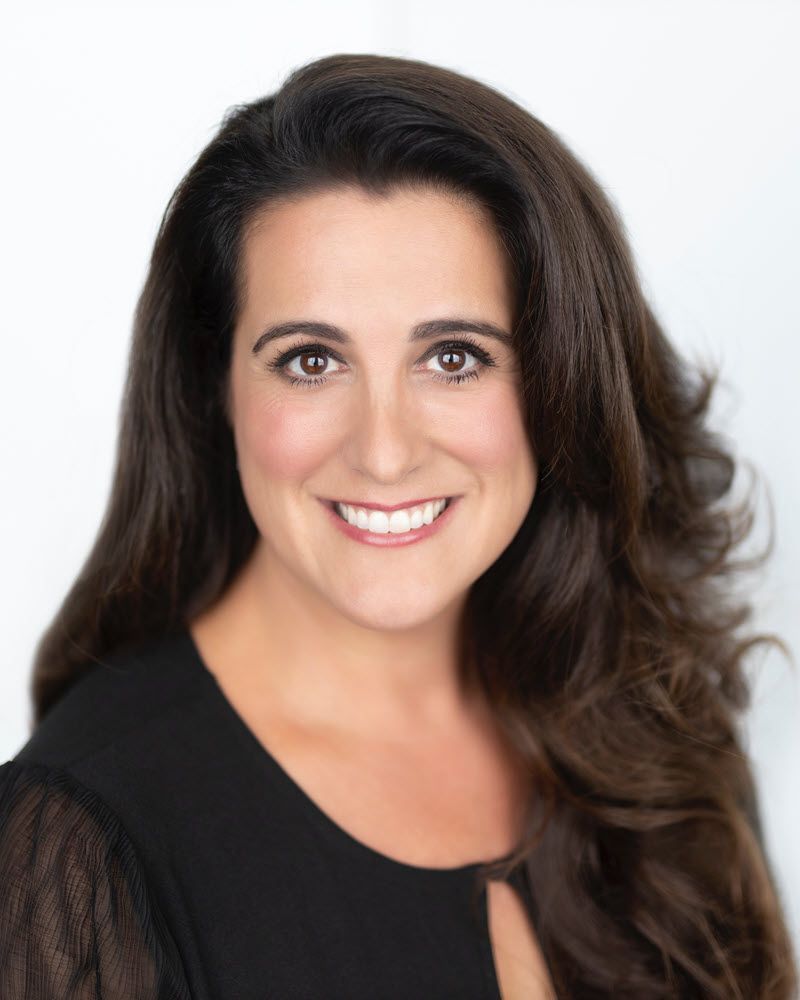 Agent Donna with long brown hair is smiling and wearing a black shirt.