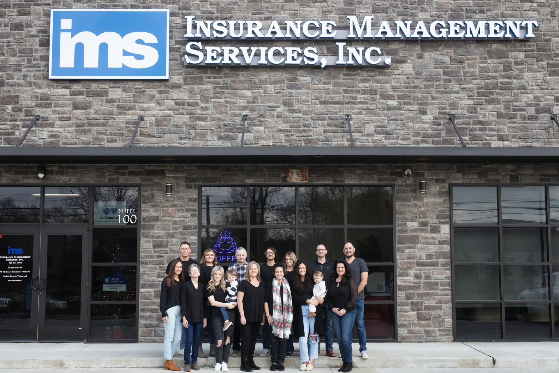 A group of people standing in front of an insurance management services inc. building.