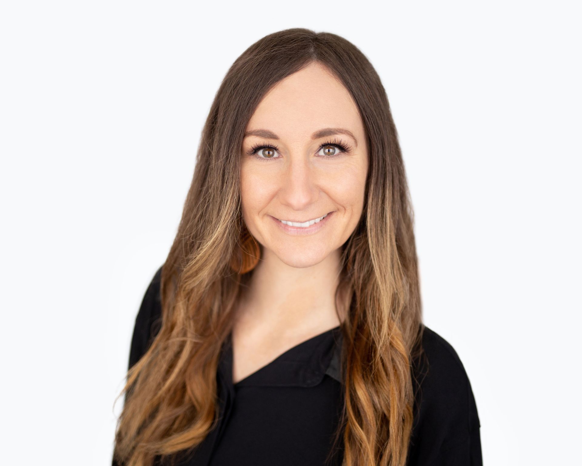 Office Manager Kelly with long brown hair is wearing a black shirt and smiling.