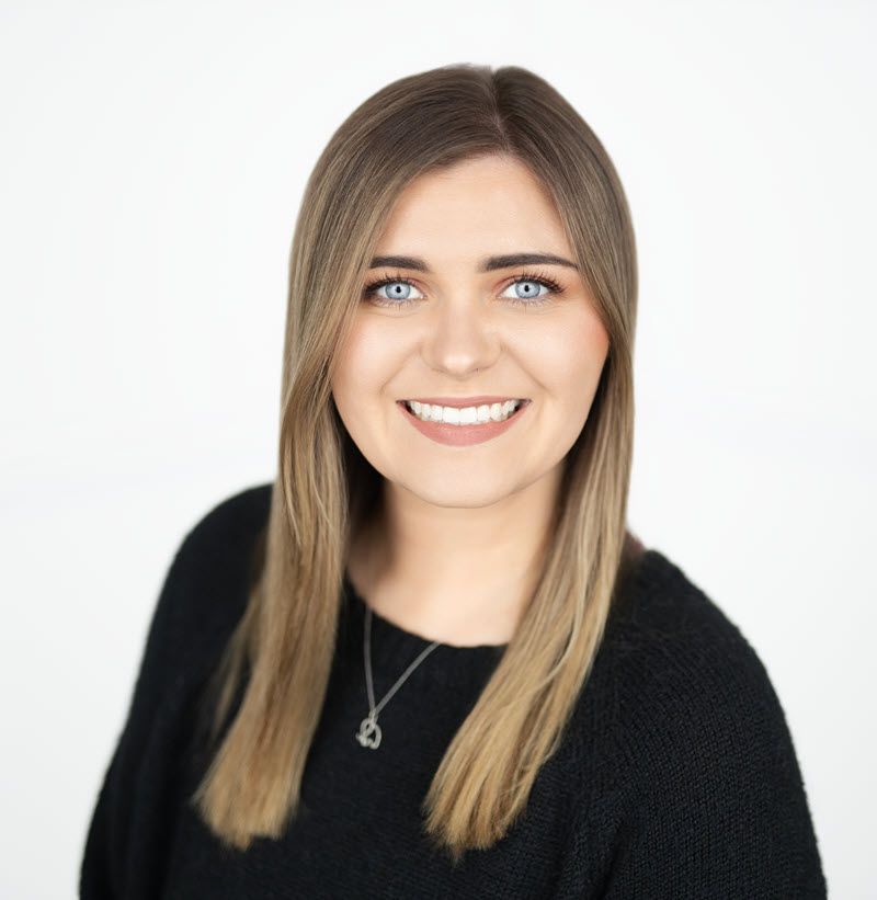 Agent Assistant Zoe in a black shirt is smiling for the camera.