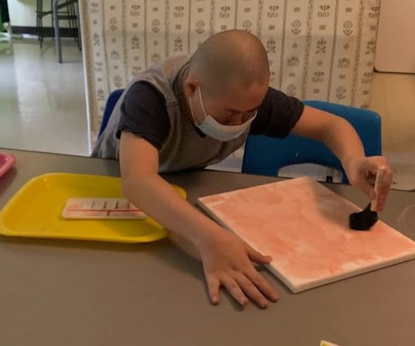 Landscape painting of rolling hills with a path, green patches, and a pink and yellow sky.