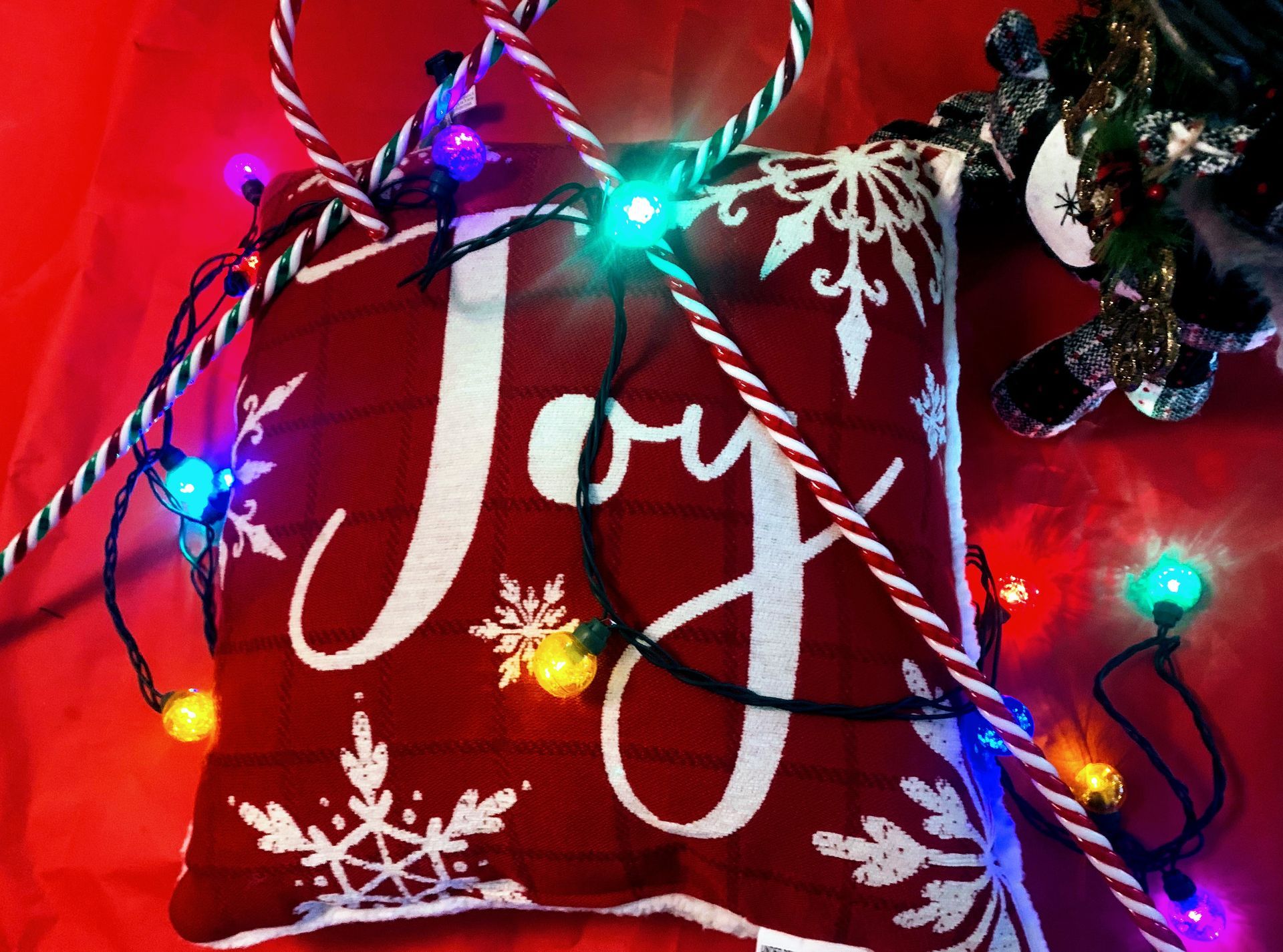 A red rose in a blue vase on an easel, other paintings hang on a dark blue wall.