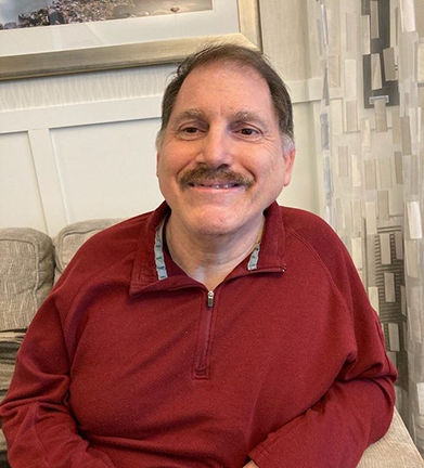 Young person with light skin, long hair, smiling, outdoors.