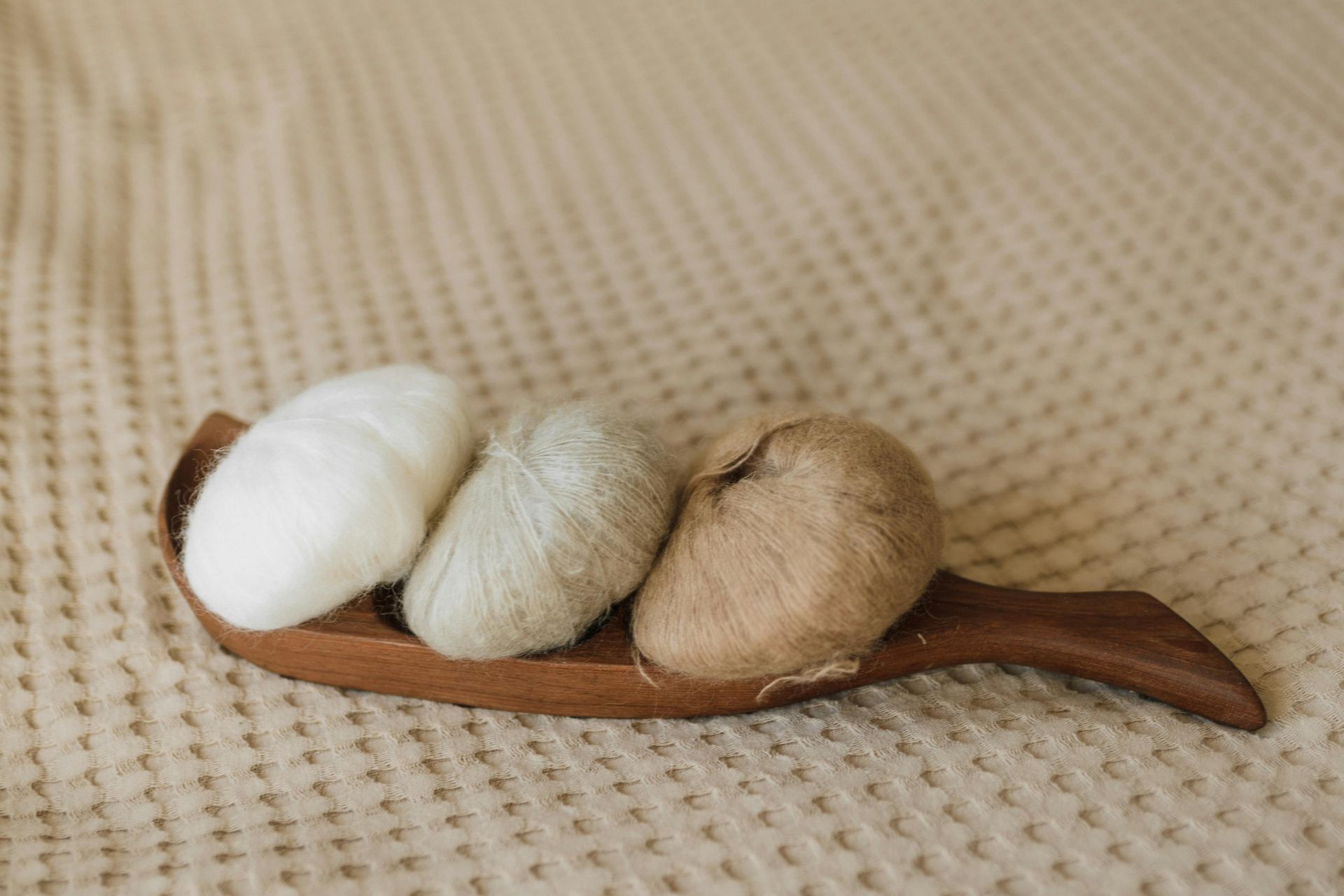 A set of loose wool balls on a wooden spoon.