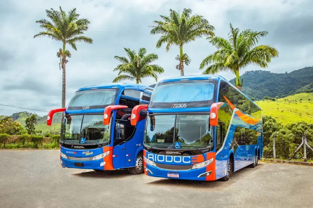 Dois ônibus azuis estão estacionados um ao lado do outro em um estacionamento.