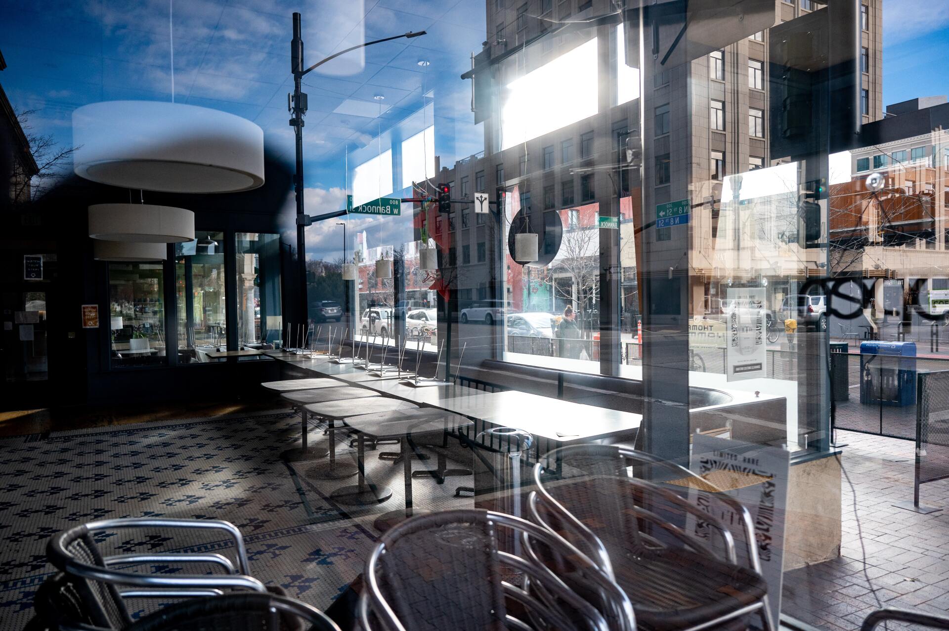 A restaurant with tables and chairs and a reflection of a city in the windows