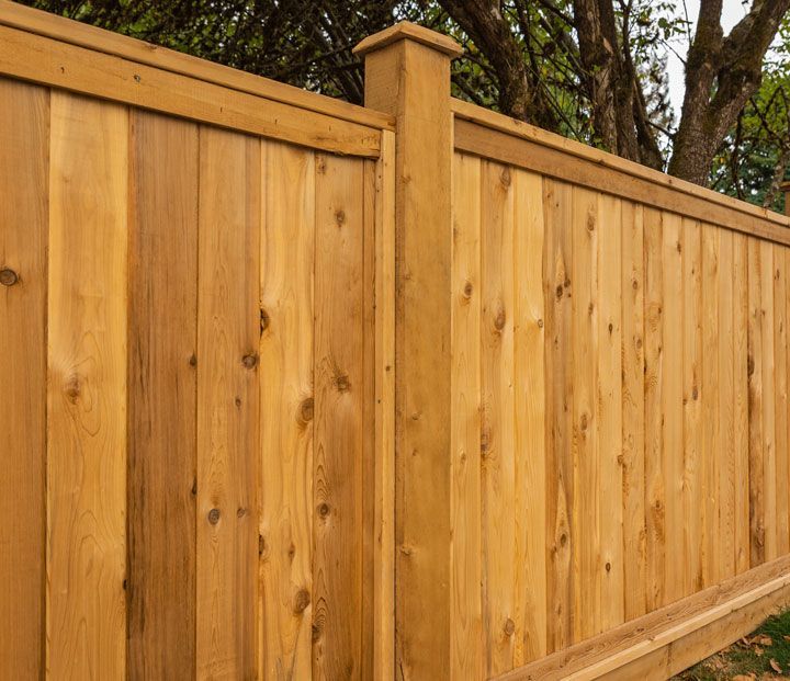 Nice new wooden fence around house. Wooden fence with green lawn.