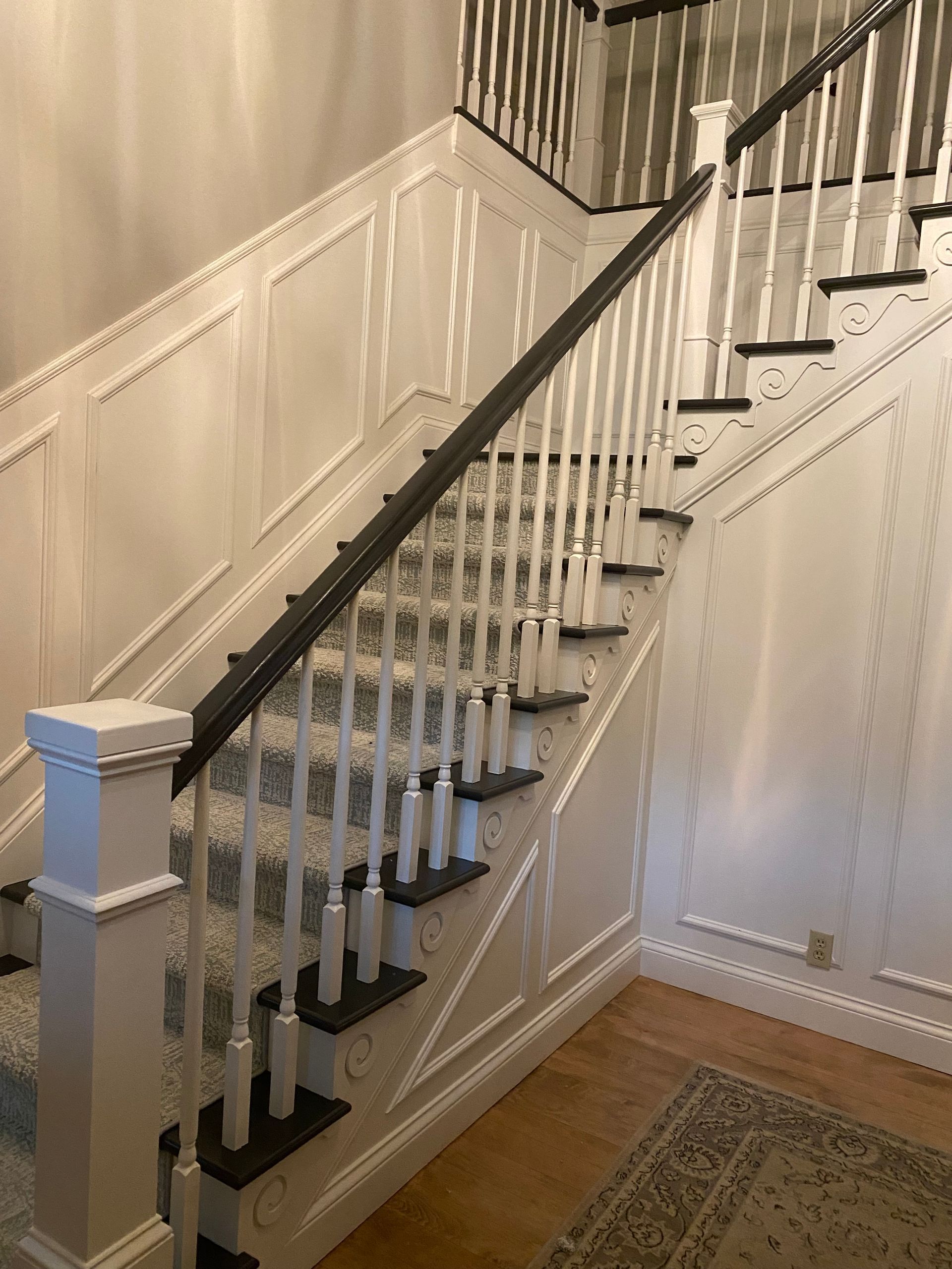 A staircase with white railings and black steps in a house.