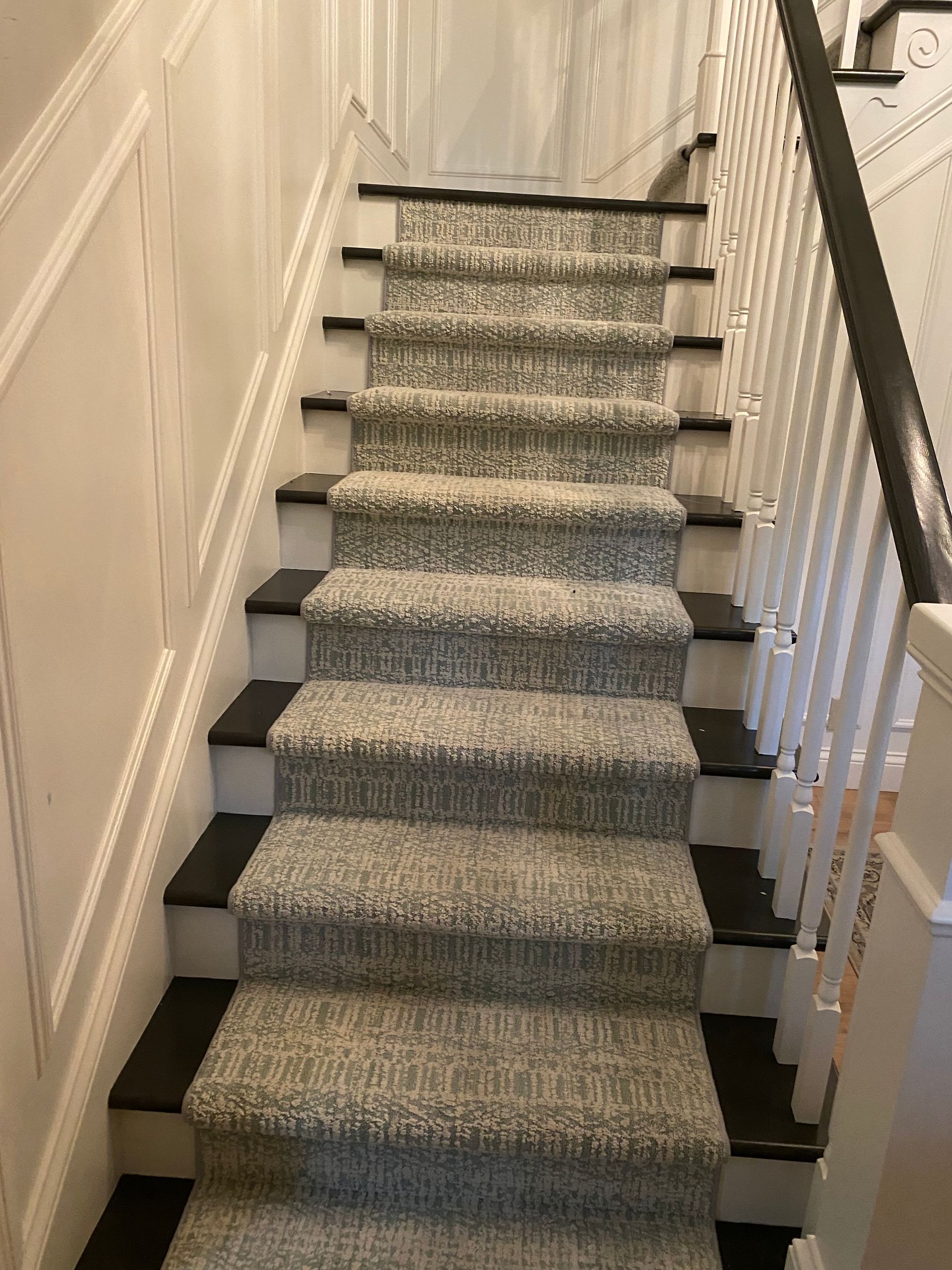 A staircase with a carpet on the steps and a black railing.