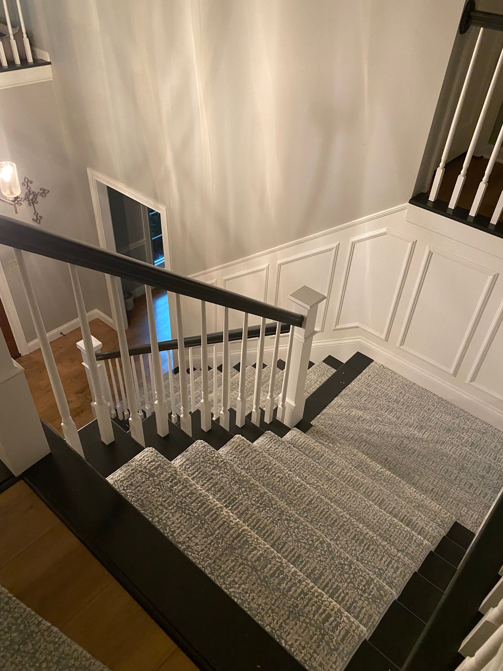 An aerial view of a staircase with a black railing and a gray carpet.