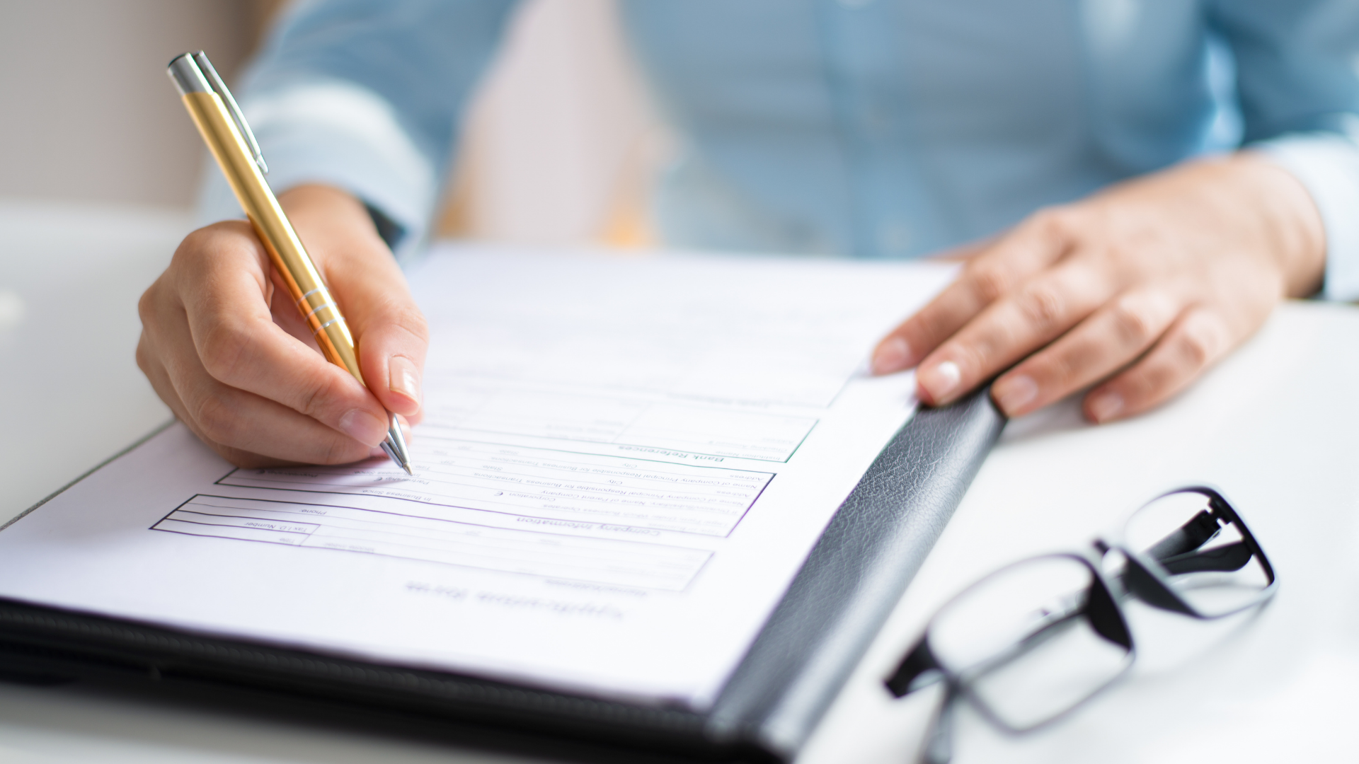 A person is writing on a piece of paper with a pen.