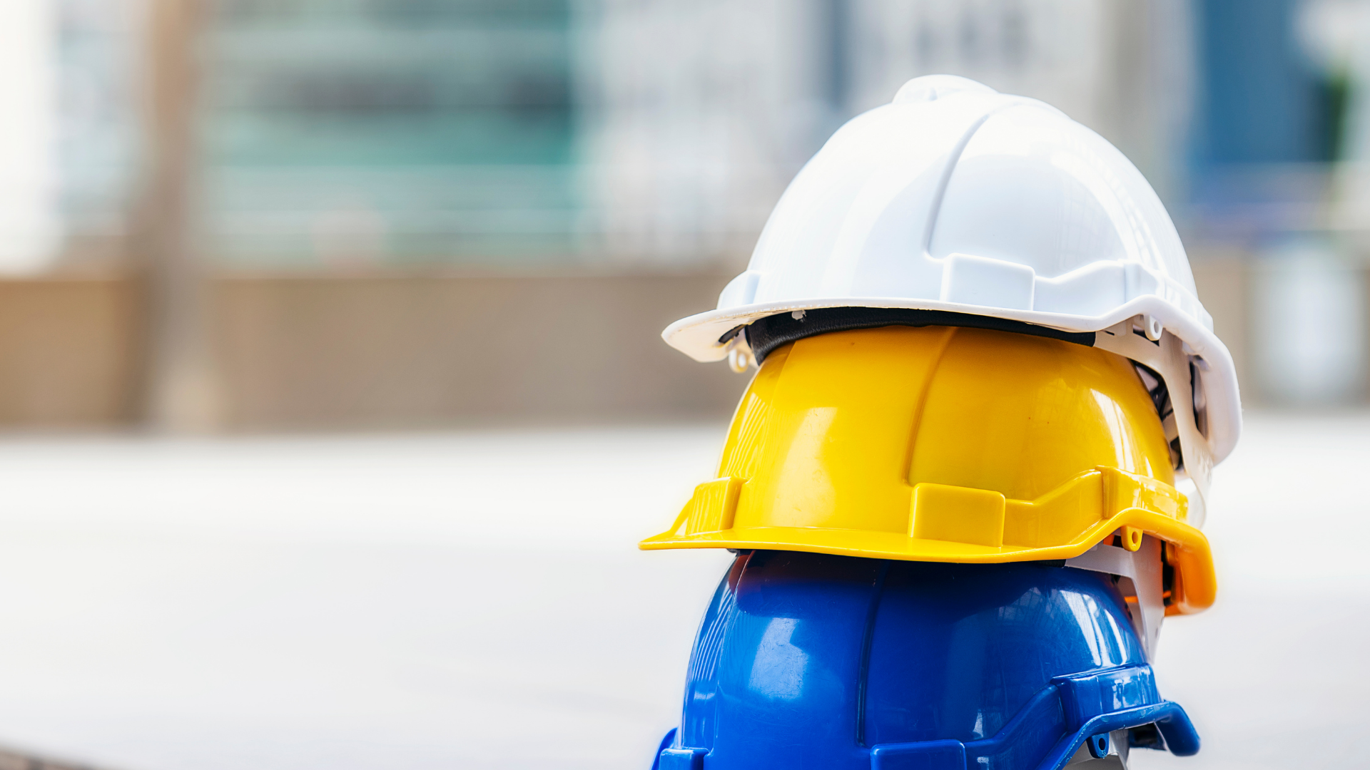 Three hard hats are stacked on top of each other on a construction site.