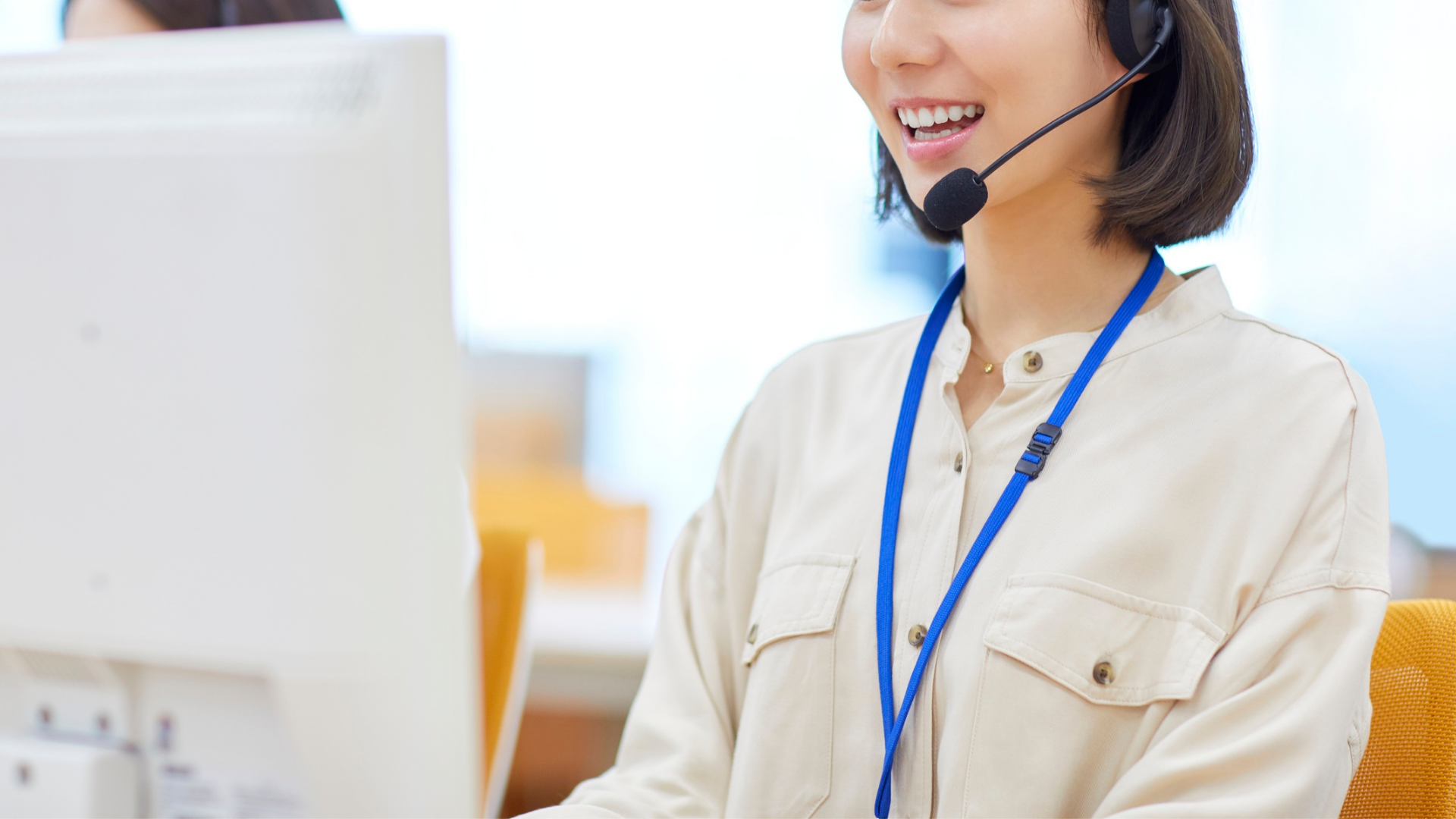 A woman wearing a headset is sitting in front of a computer.