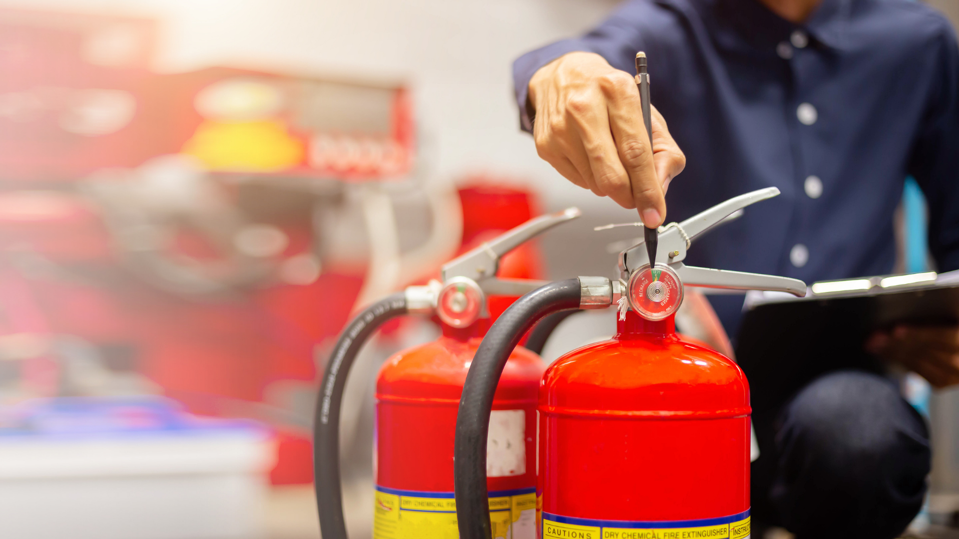 A man is fixing a fire extinguisher while looking at a tablet.