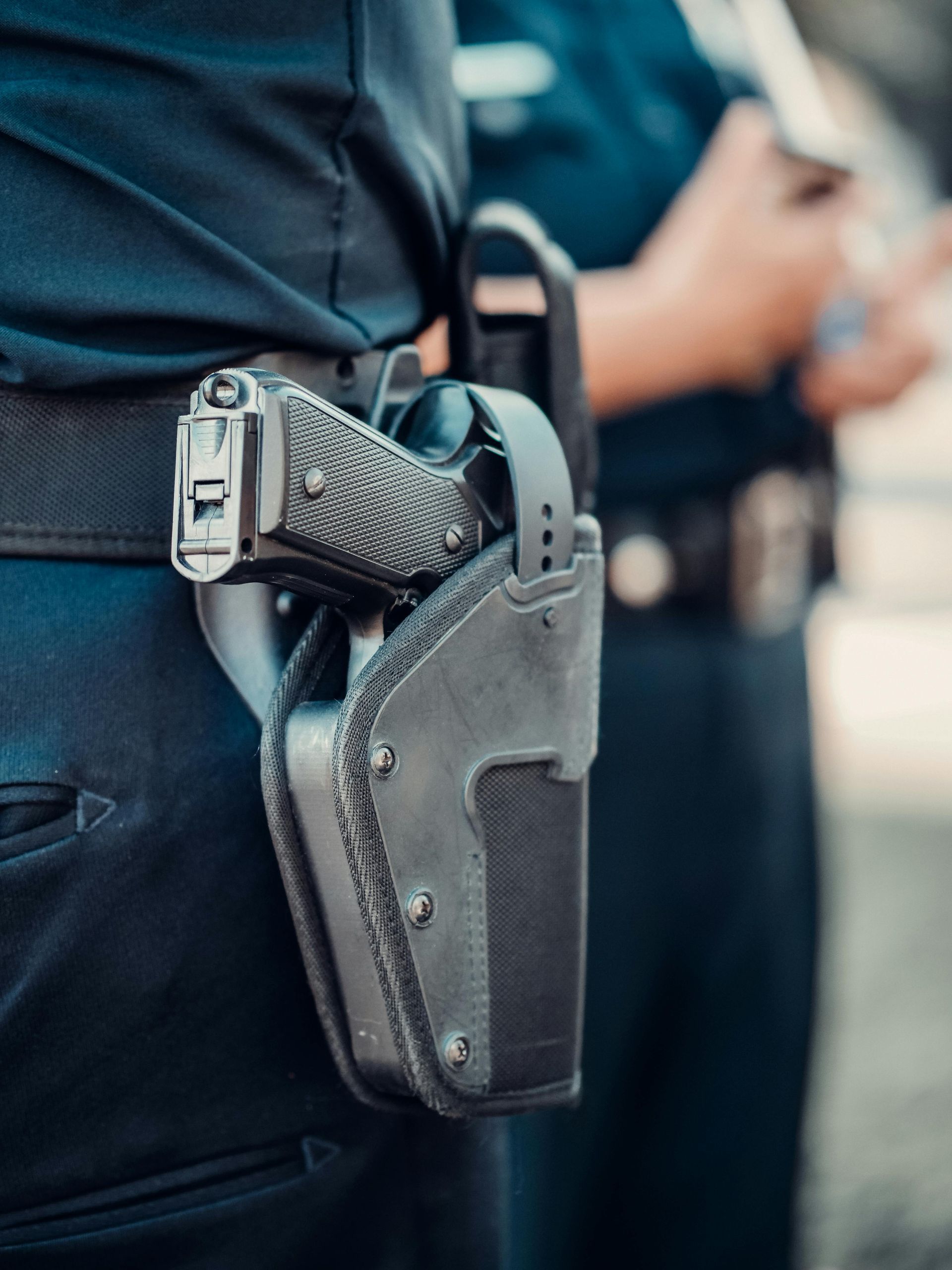 Close-up of a holstered handgun on a police officer's belt.