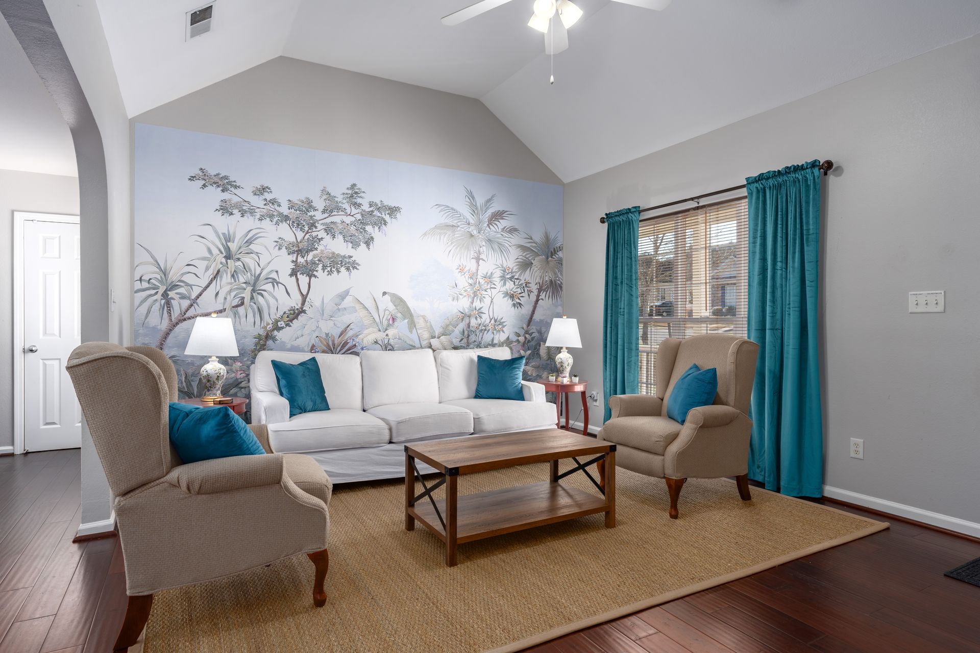 A living room with a couch , chairs , coffee table and a painting on the wall.