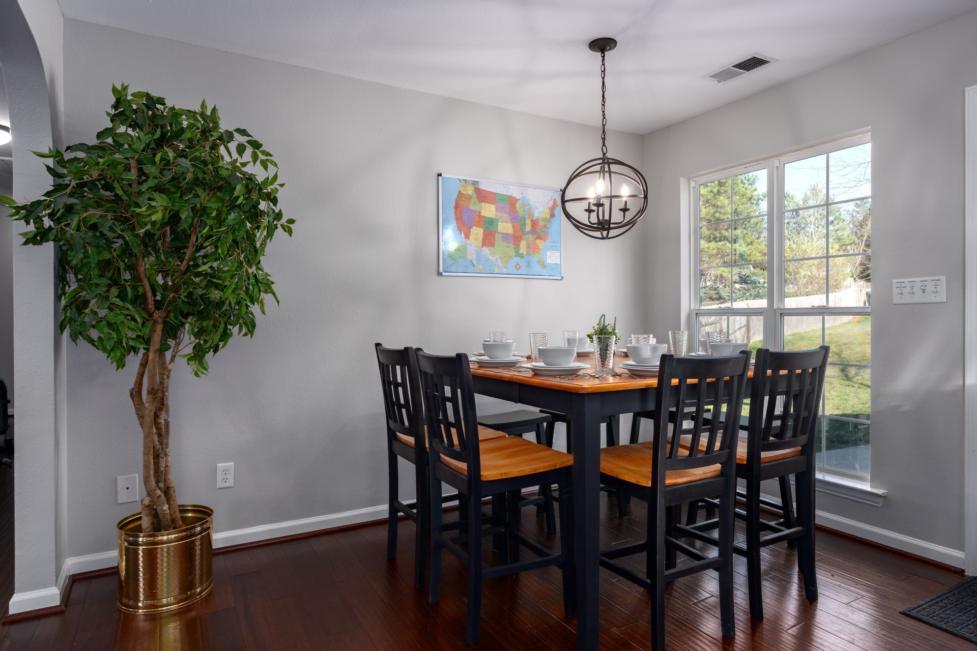 A dining room with a table and chairs and a potted plant.