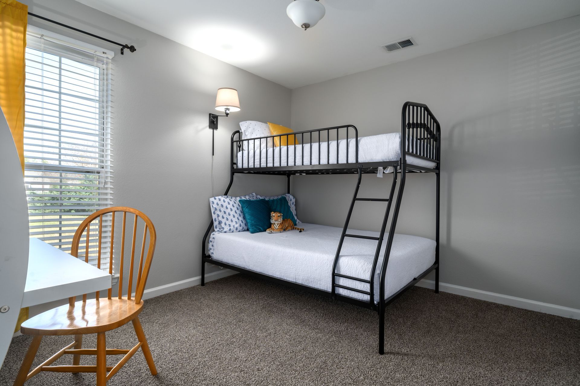A bedroom with a bunk bed , chair , desk and window.