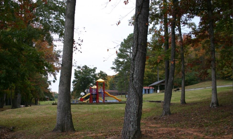 An aerial view of a park with a playground and tennis courts.