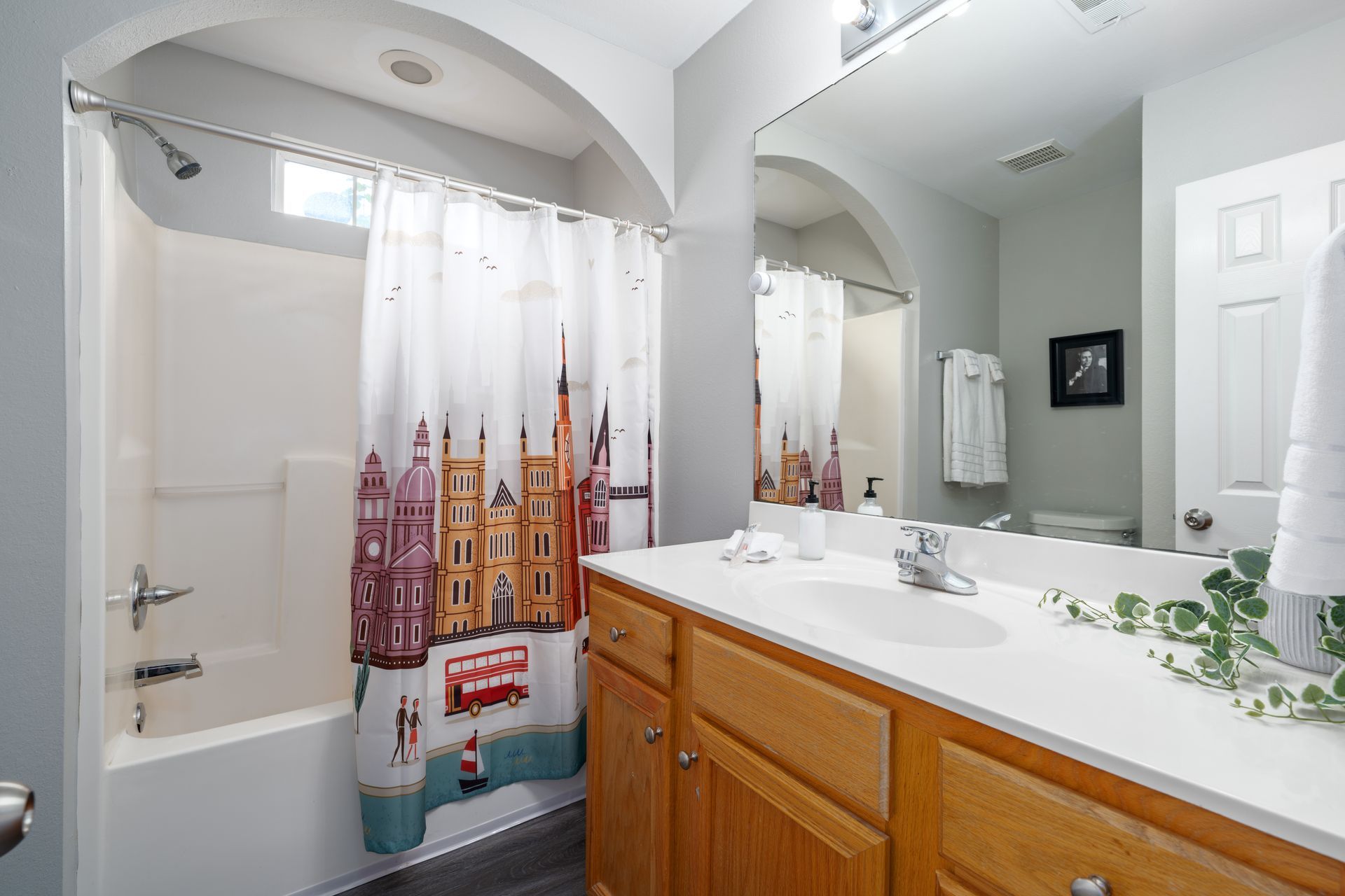A bathroom with a bathtub , sink , mirror and shower curtain.