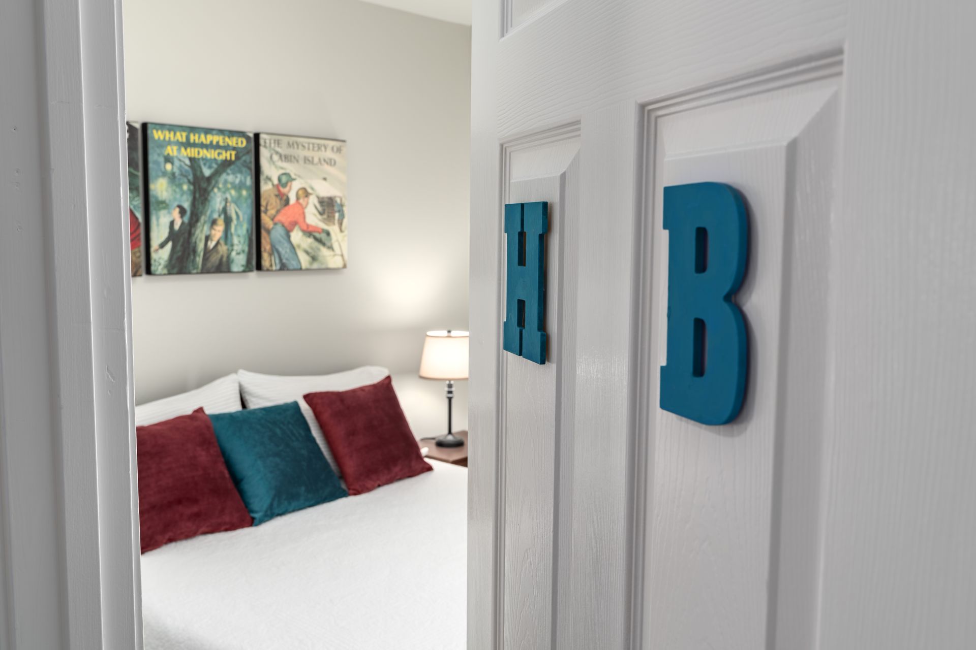 A bedroom with a bed and two doors with the letter b on them.