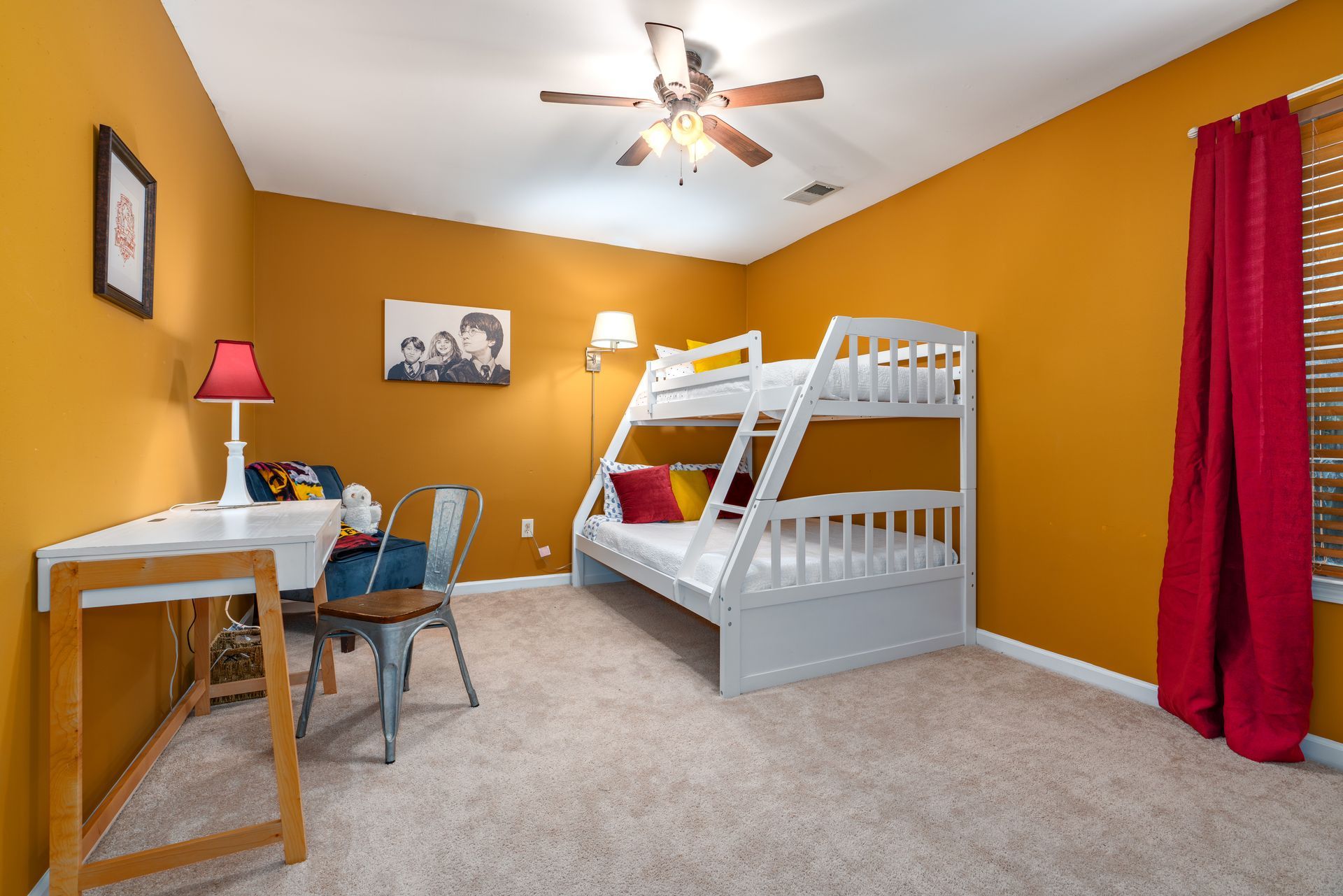 A bedroom with bunk beds , a desk , chairs and a ceiling fan.