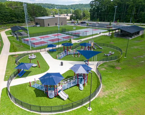 An aerial view of a park with a playground and tennis courts.