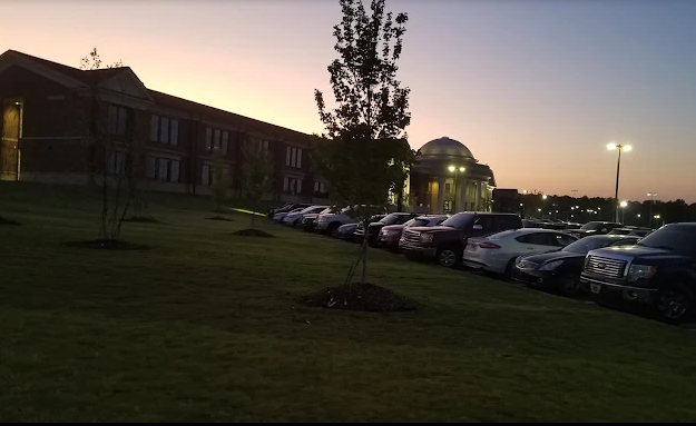 A row of cars are parked in front of a building at night