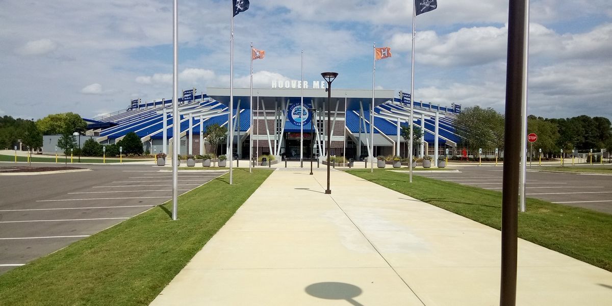Stadium exterior with blue and white architecture under a cloudy sky.