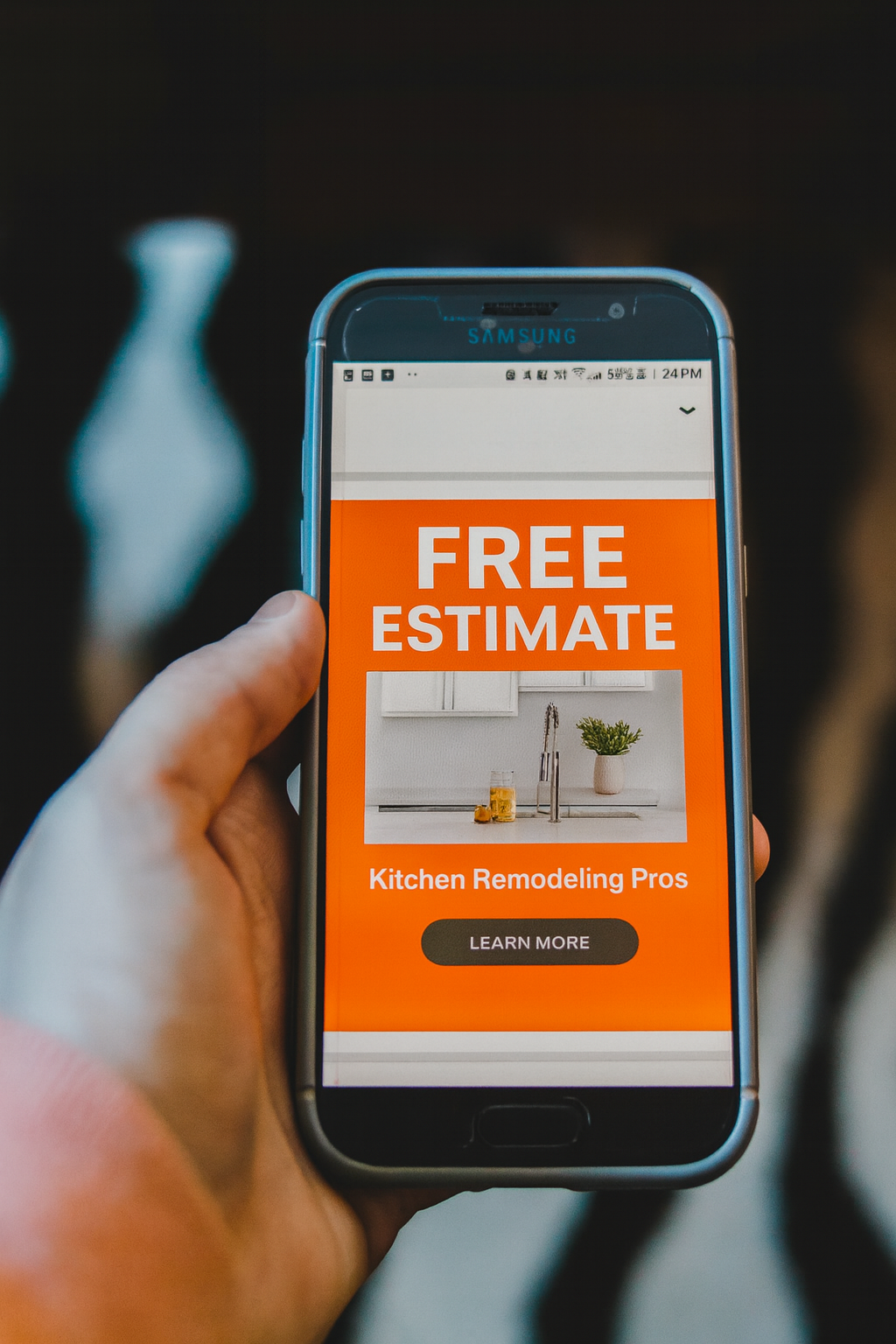 Hand holding phone displaying a home remodeling ad, offering a free estimate.
