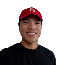 Smiling young man (Jian Marco) wearing a red Cardinals hat and black shirt.
