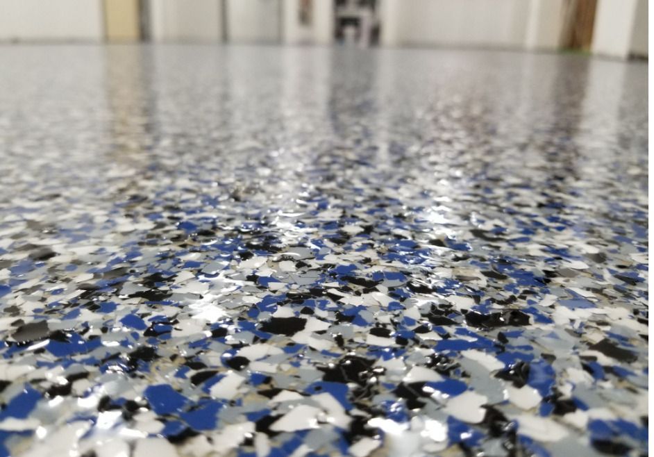 Close-up of a glossy, speckled epoxy floor with blue, black, white, and gray flakes.